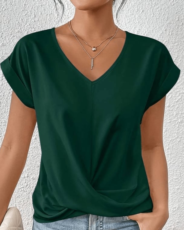 Woman wearing a green V-neck twist front short sleeve top with a gathered knot hem detail, front view