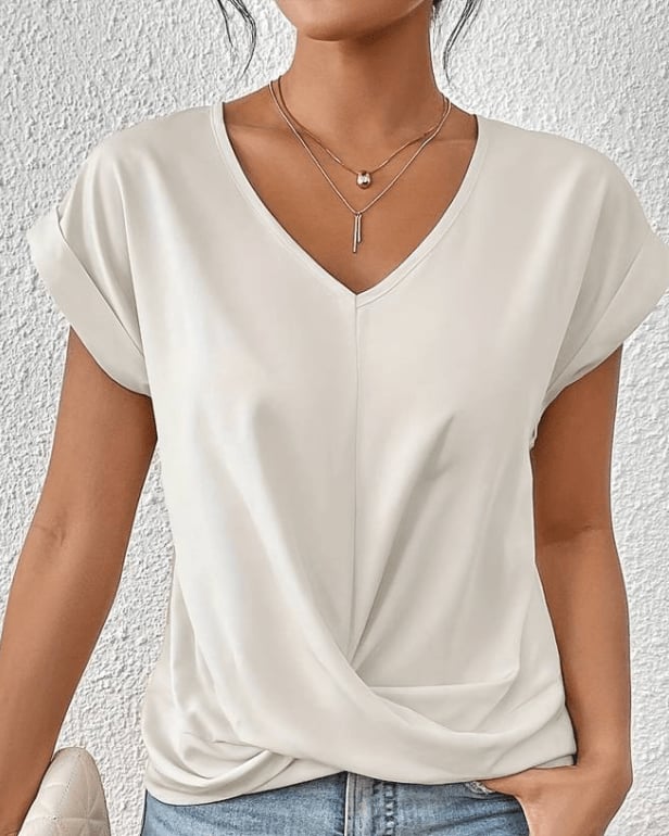 Woman wearing a navy V-neck twist front top styled with high-waisted jeans, front view