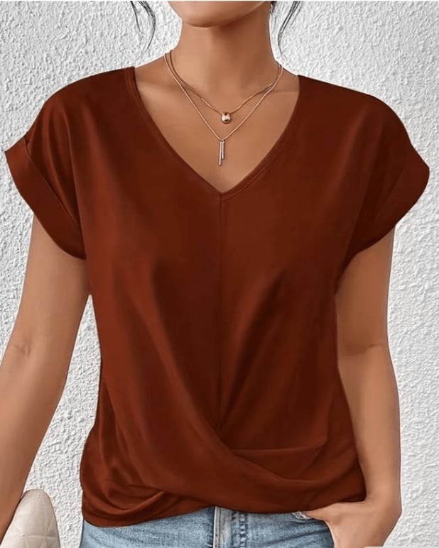 Woman wearing a pink V-neck twist front top with cuffed cap sleeves, three-quarter view