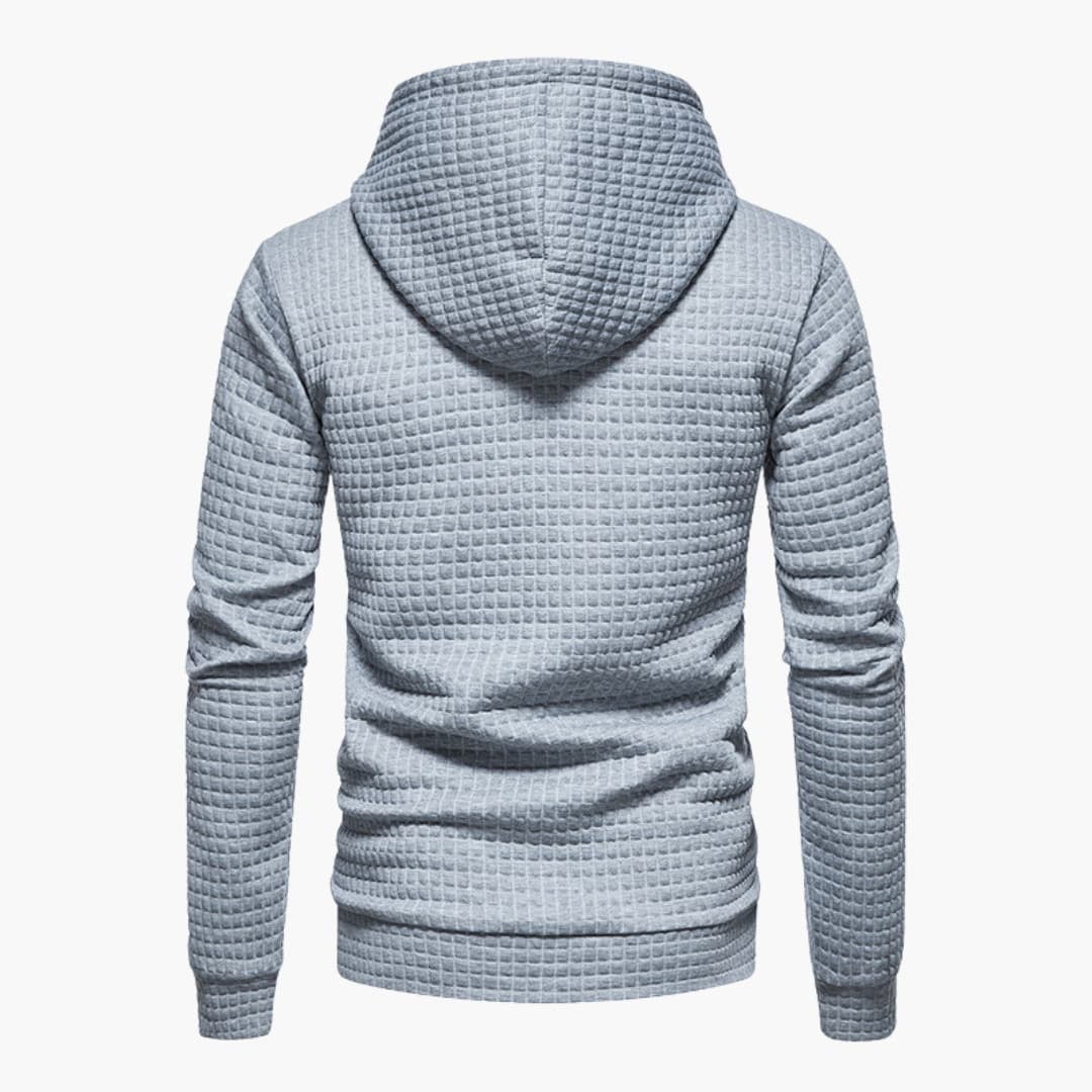 Model smiling in the dark grey Jasper Comfort Hoodie in an outdoor setting