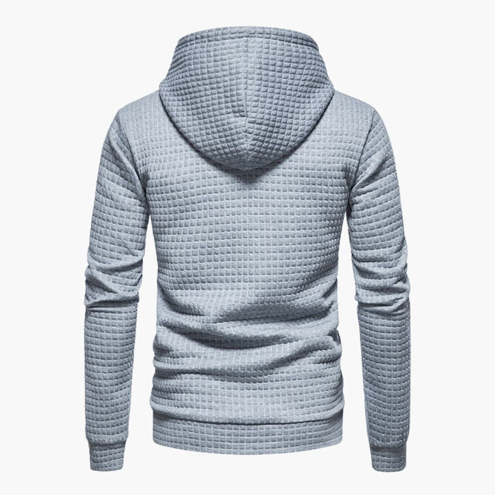 Model smiling in the dark grey Jasper Comfort Hoodie in an outdoor setting