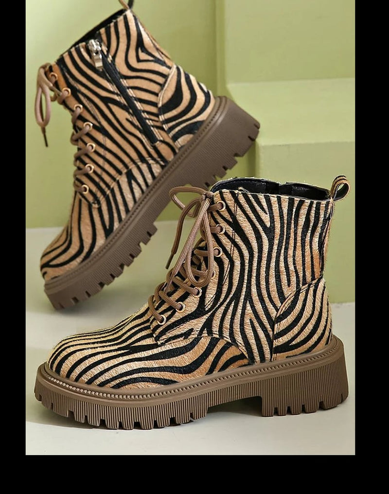 Khaki zebra print lace-up boots shown from the front, featuring black-and-white animal print pattern and secure lacing