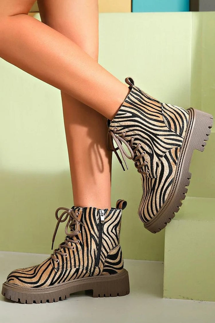 Close-up detail of zebra print lace-up boots showing the bold black-and-white pattern and lacing hardware
