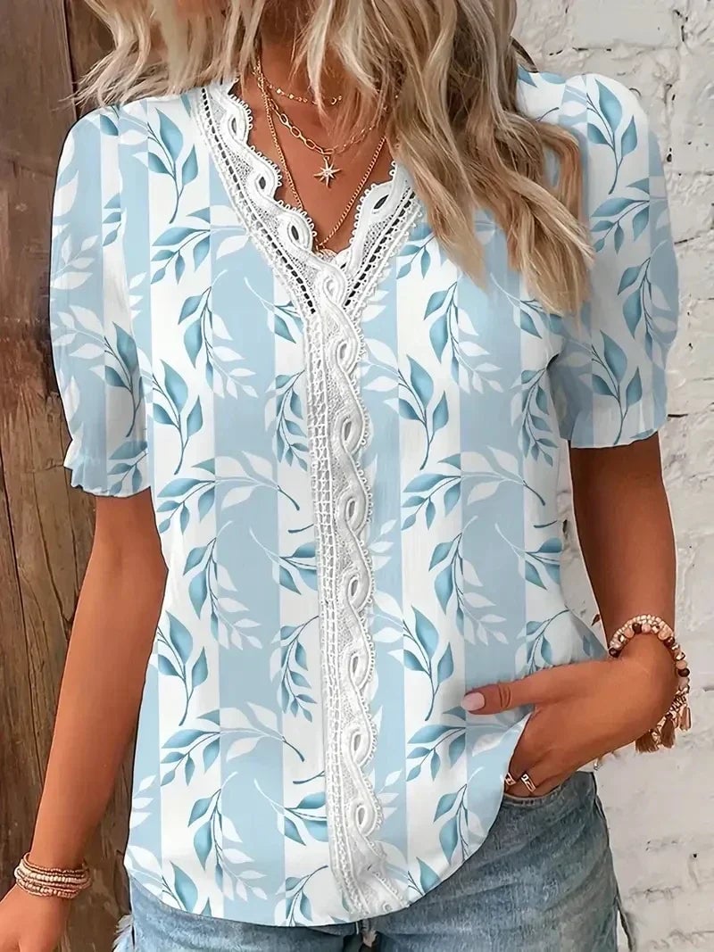 Woman wearing a light blue floral lace V-neck blouse with a relaxed fit, front view