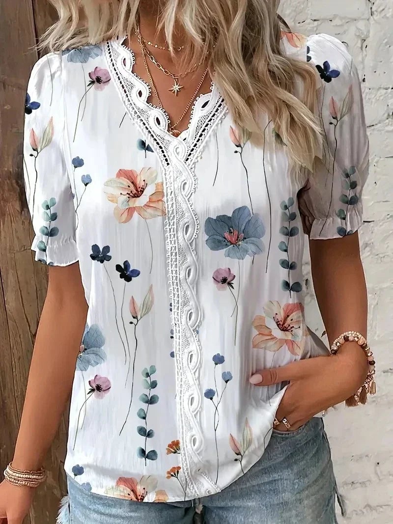 Model styling a white floral lace V-neck blouse tucked into high-waisted trousers