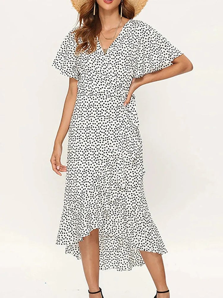 Front view of a floral maxi dress in white with delicate ruffle detailing and an elegant side slit