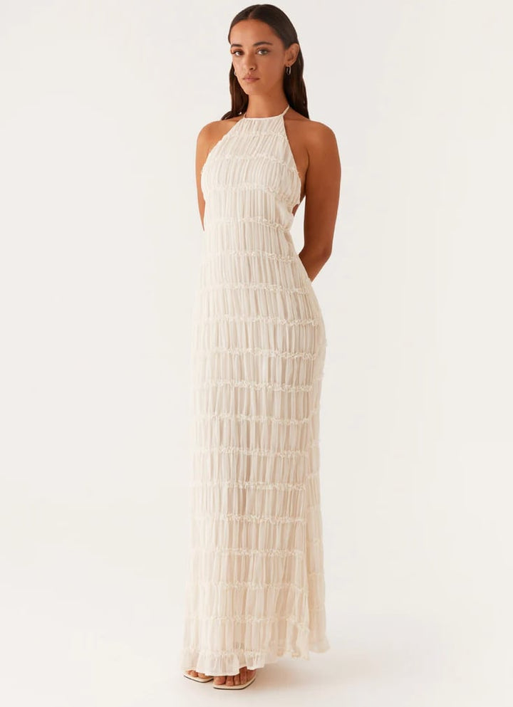 Woman wearing a pink halter maxi dress with flowing skirt and adjustable tie neckline, front view