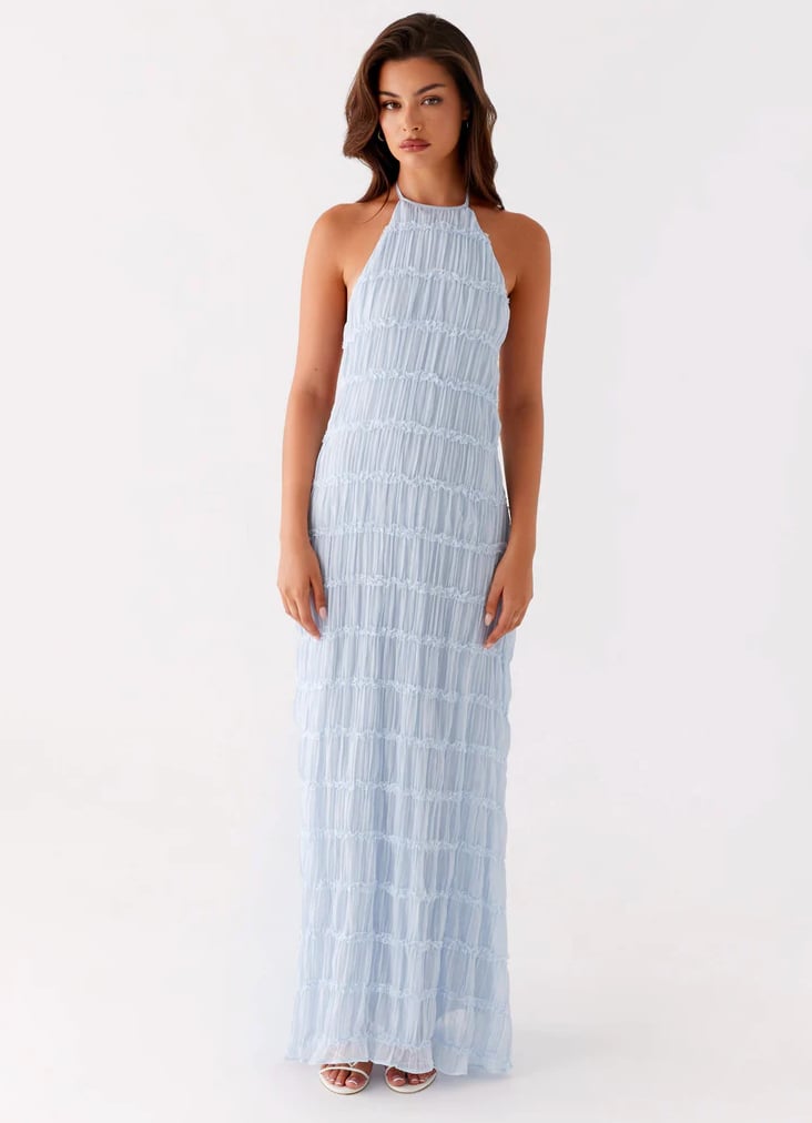 Woman in elegant pink halter maxi dress posing to show fitted bodice and full-length flowing skirt