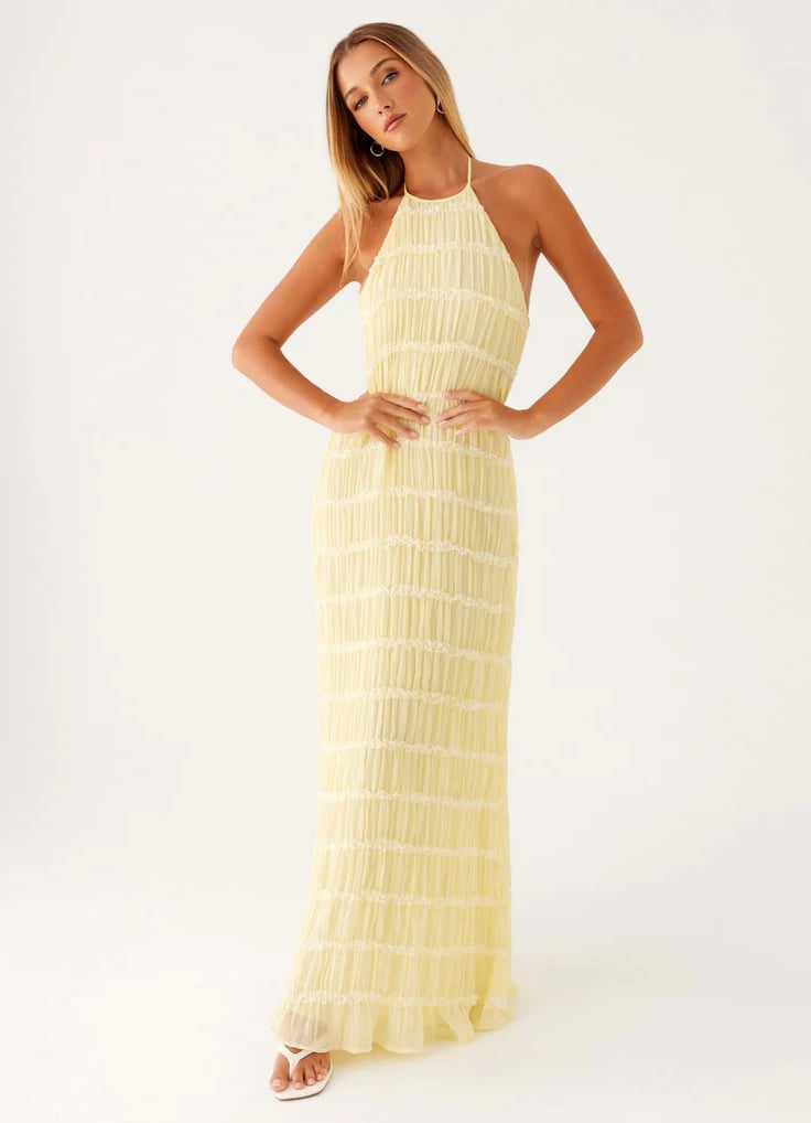 Side profile of model in pink halter maxi dress highlighting invisible side zipper and clean silhouette