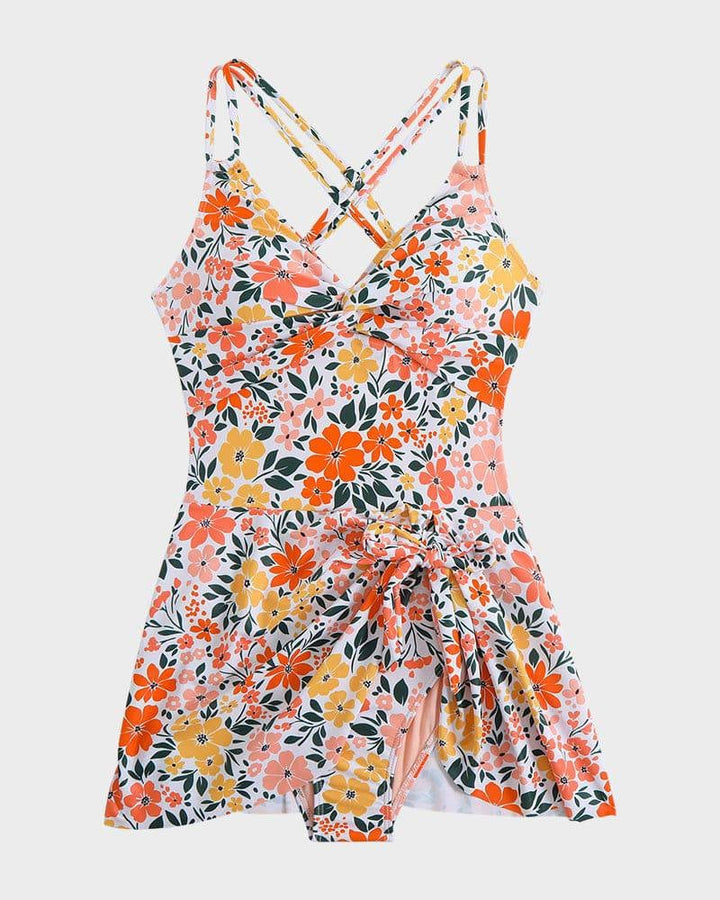 Woman in pink floral swim dress laughing and enjoying the beach, dressed in a flattering one-piece swimsuit