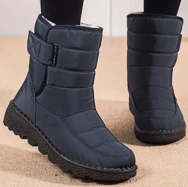 Women's waterproof boots in red worn outdoors on wet pavement