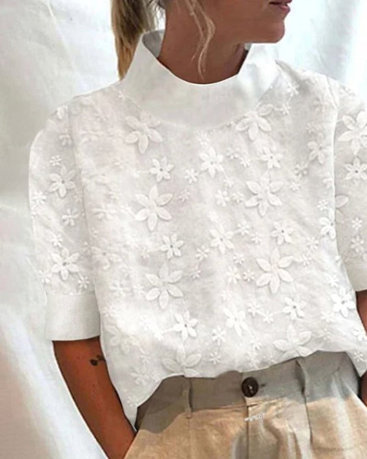 Woman wearing a white floral embroidery stand-up collar blouse with a relaxed, polished fit