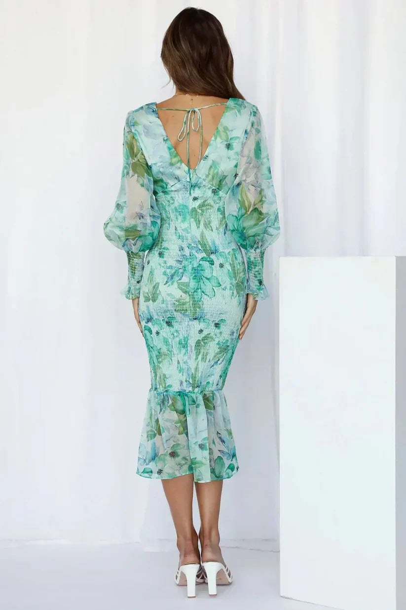 Model styled in the Julia floral dress in green with accessories for a wedding guest look