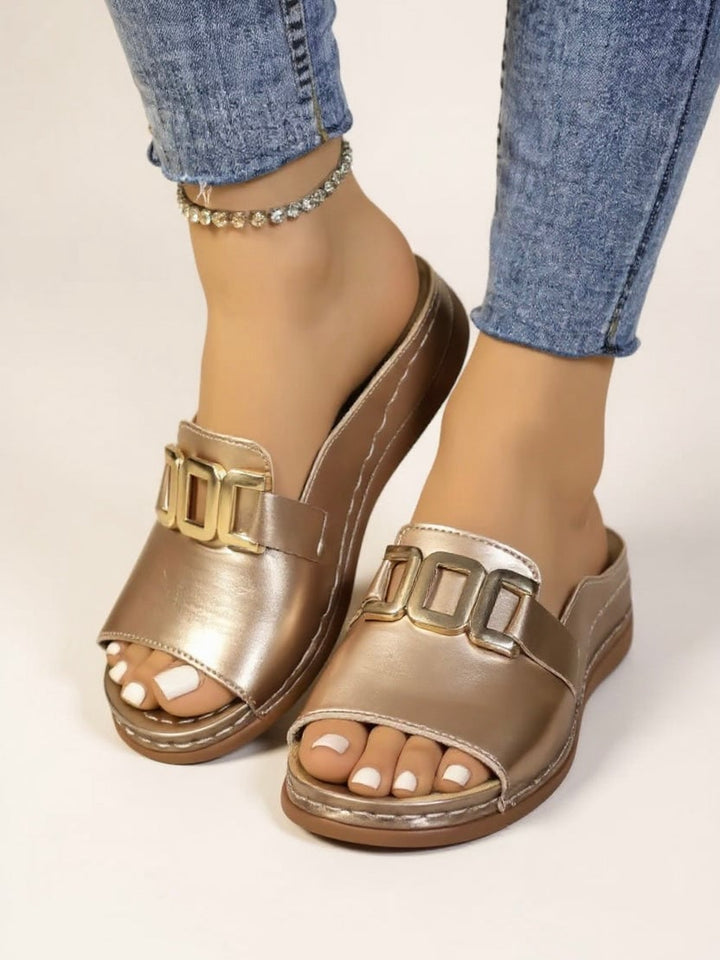 Close-up of the gold buckle detail on Juno cushioned slides