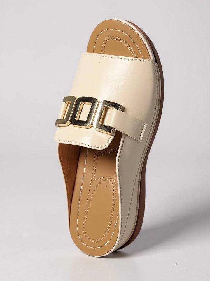 Juno slides in beige worn by a model walking on a sun-lit surface