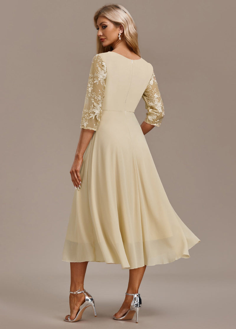 Back view of champagne floral 3/4 sleeve dress highlighting round neckline and elegant drape