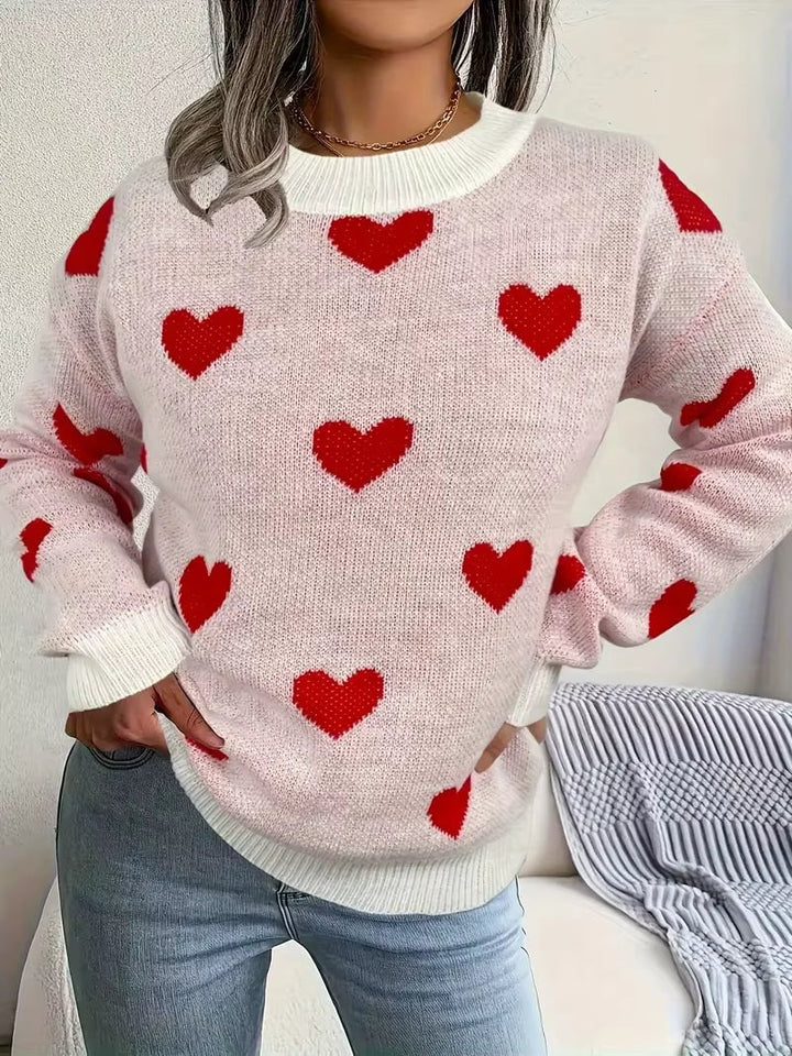 Woman wearing a white relaxed-fit sweater with a subtle heart pattern, styled with jeans