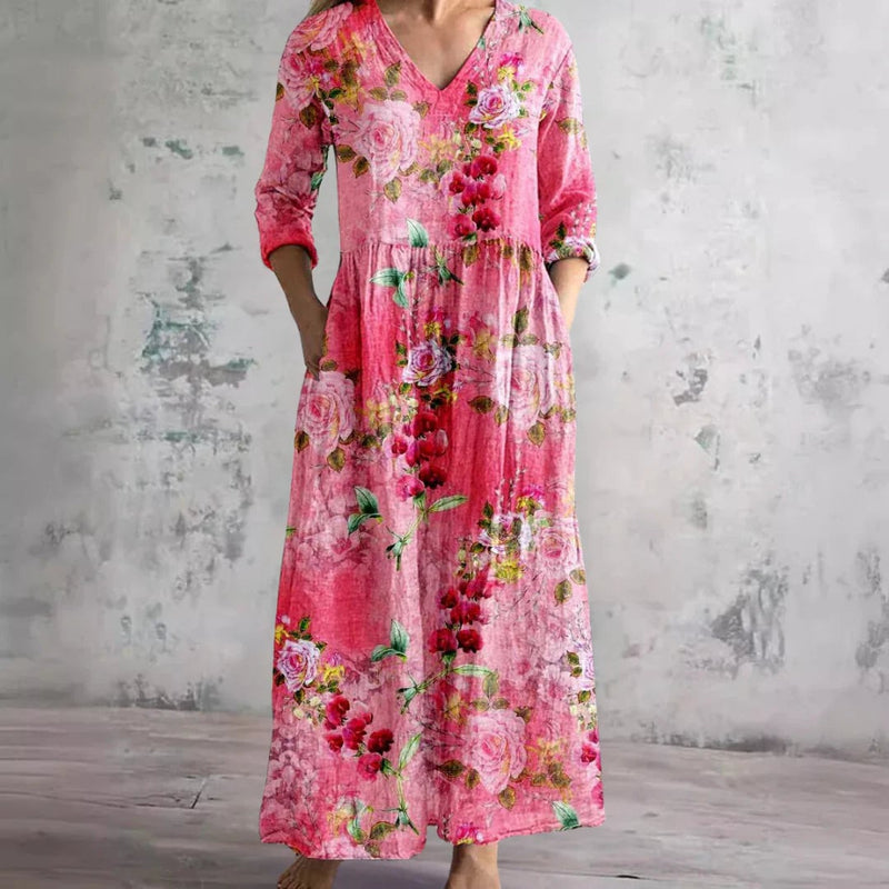 Woman wearing a pink floral v-neck maxi dress with a flowing silhouette and elegant drape