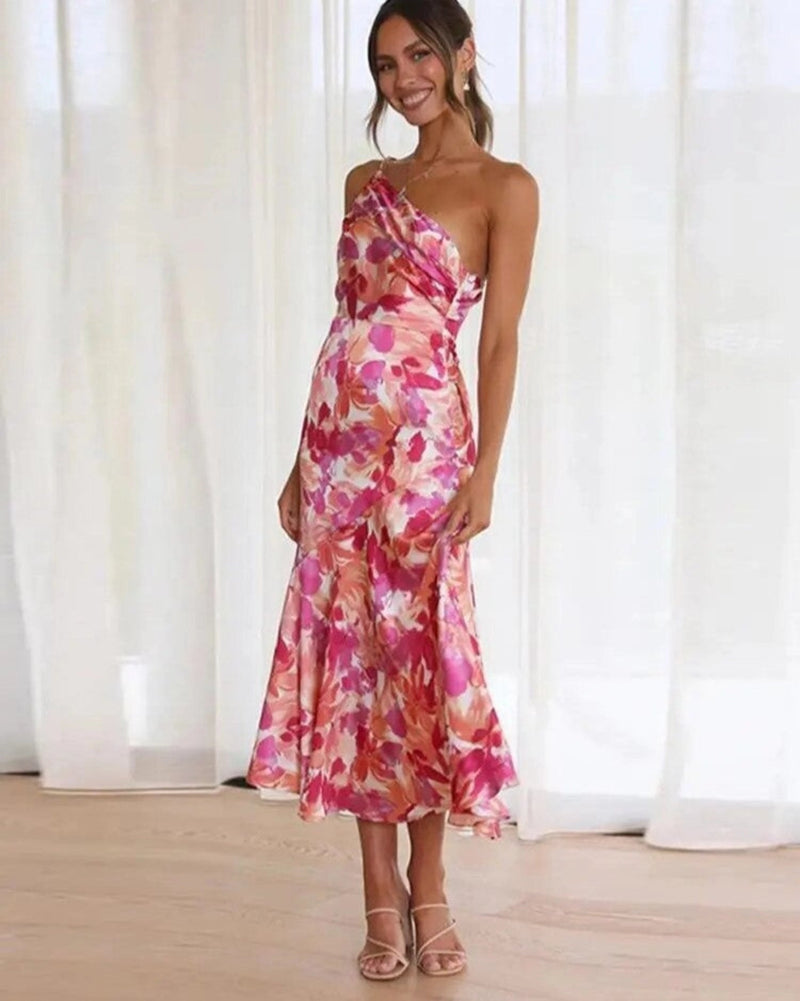 Woman wearing an orange floral one-shoulder maxi dress with an asymmetrical hem, front view