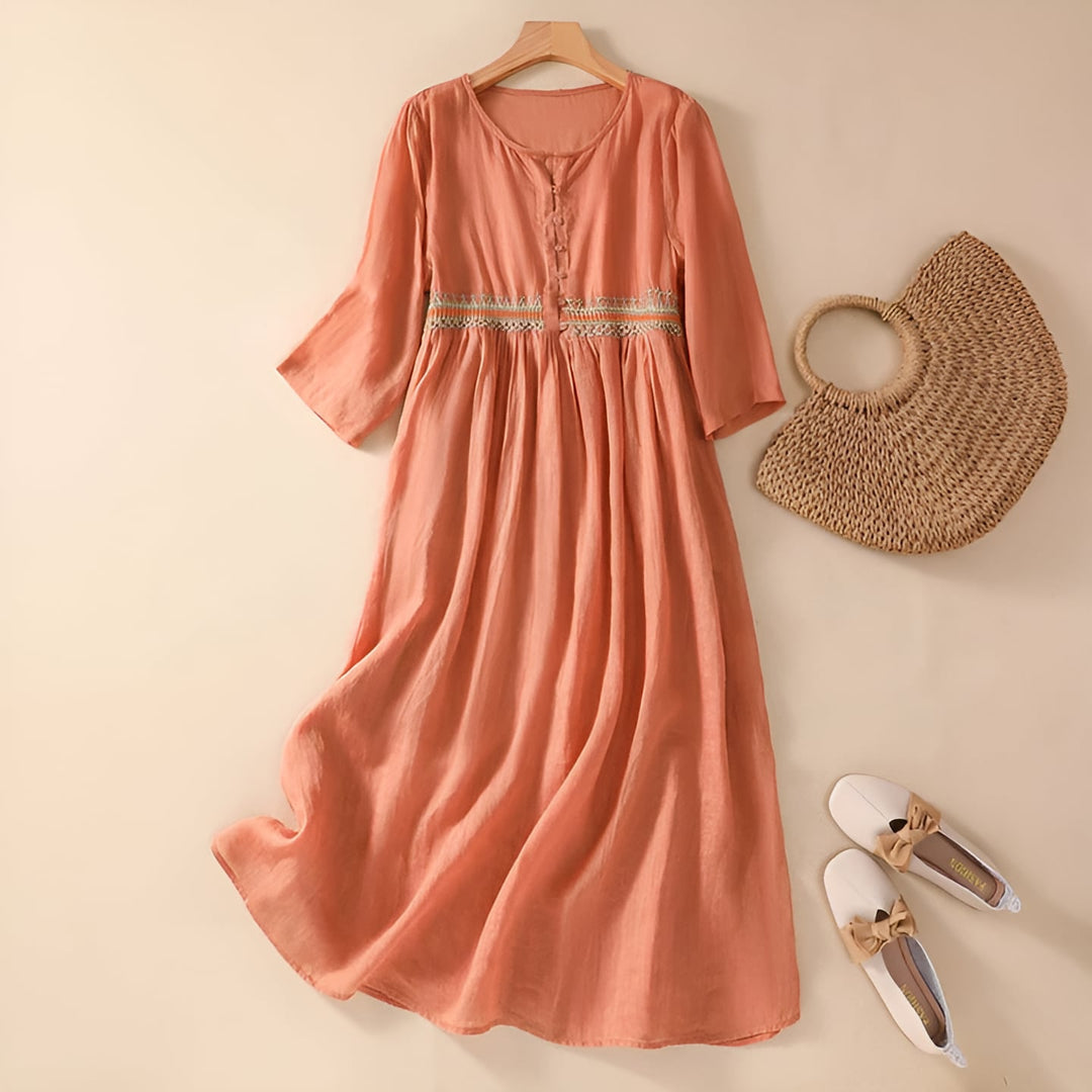 Woman in an orange embroidered midi dress showing the relaxed, flowing fit from the side