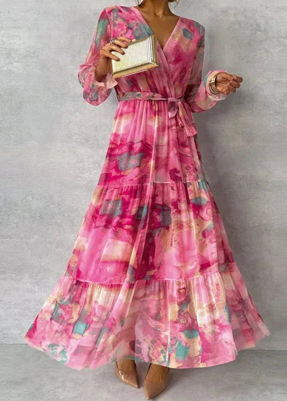 Woman wearing a flowing floral midi dress with a vibrant print and adjustable waist tie, ankle-length layered skirt