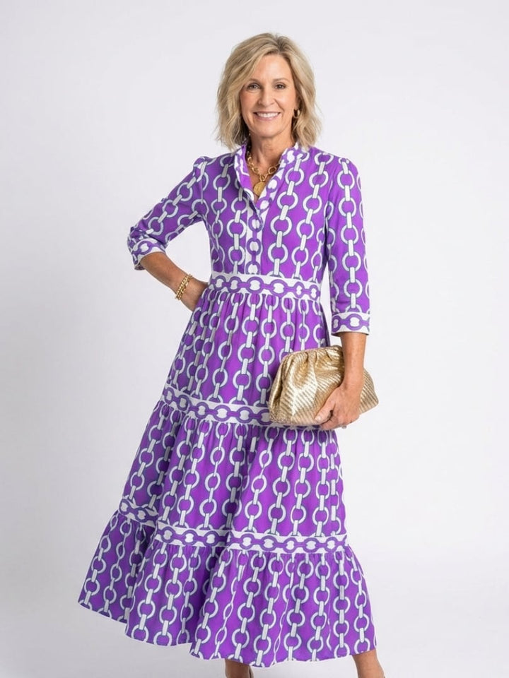 Woman wearing the Keziah chain print midi dress in purple with 3/4 sleeves and tiered hem