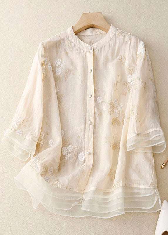 Close-up of delicate floral embroidery detail on a light beige blouse