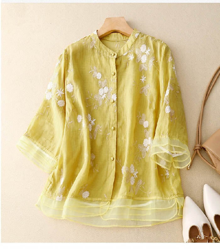 Flat lay of a beige floral embroidery blouse on a neutral background