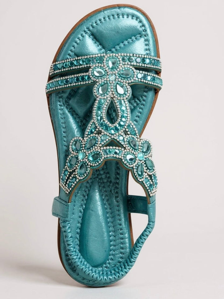 Larkspur sparkle sandals flat lay alongside a flowy summer dress and accessories