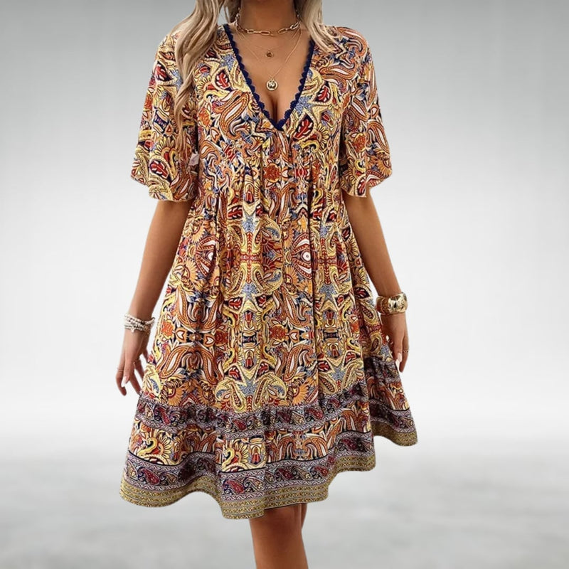 Woman wearing the Laurel paisley boho mini dress in green, standing in a sunny outdoor setting