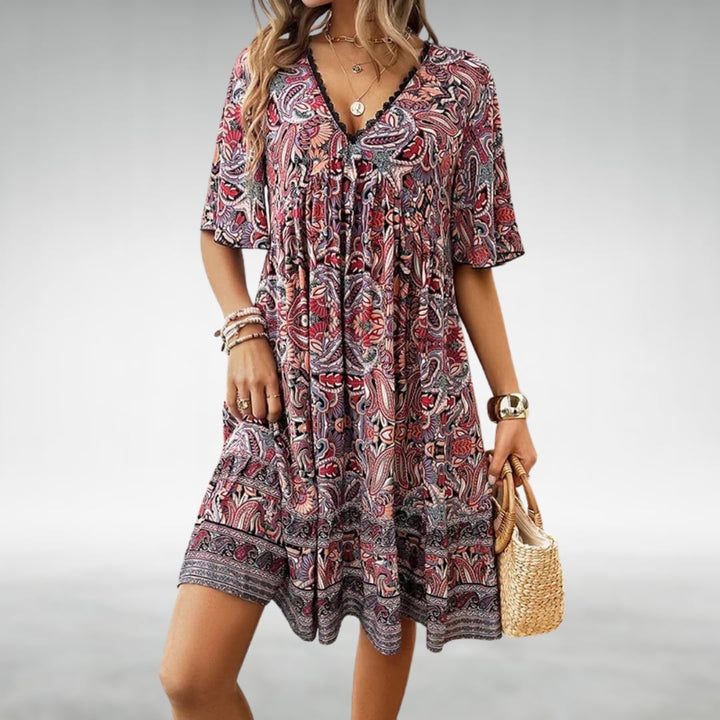 Model styling the Laurel paisley boho mini dress in yellow with sandals for a vacation look