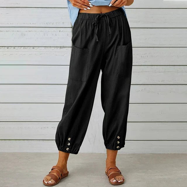 Close-up of high waist relaxed pants showing ankle button detail and deep front pocket on a female model