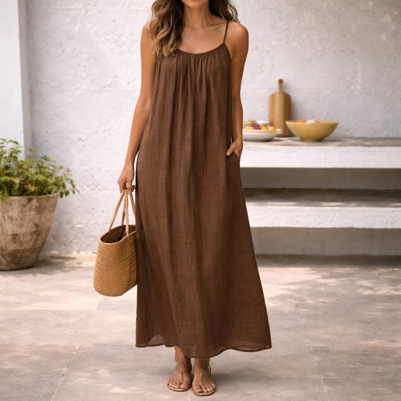 Woman wearing the Lena linen spaghetti strap maxi dress in brown with a flowing floor-length silhouette