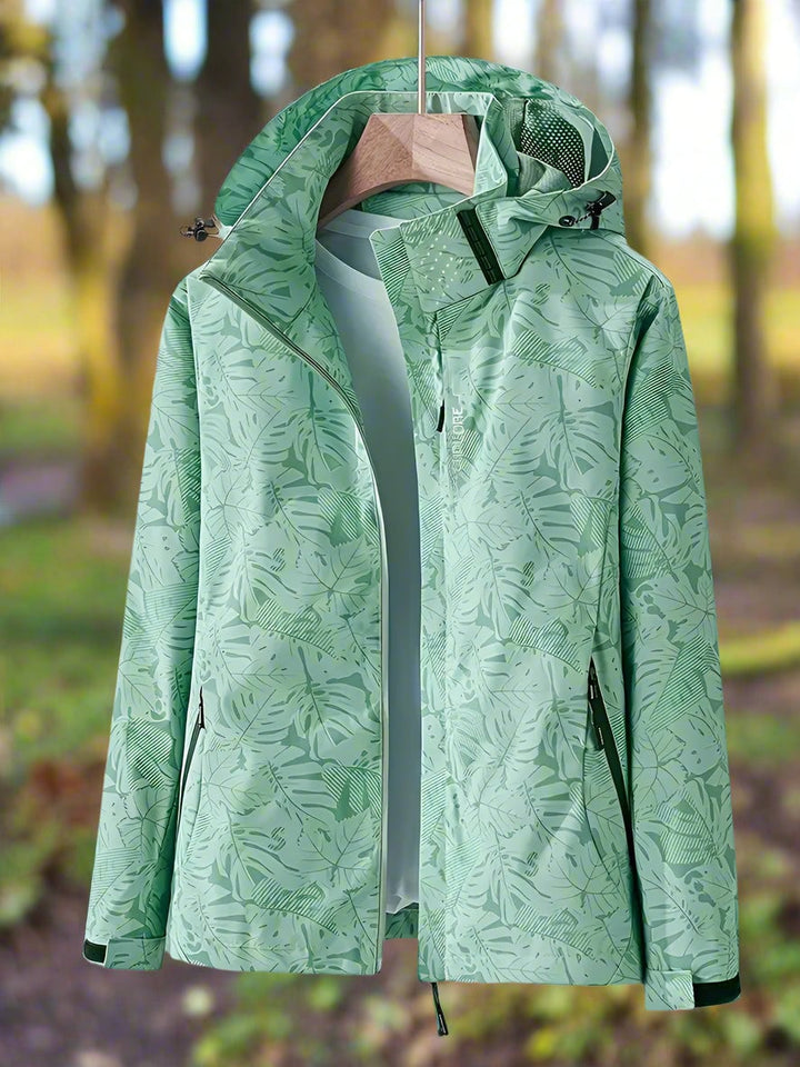 Woman wearing a green waterproof leaf-print summer jacket with adjustable hood and drawstring waist