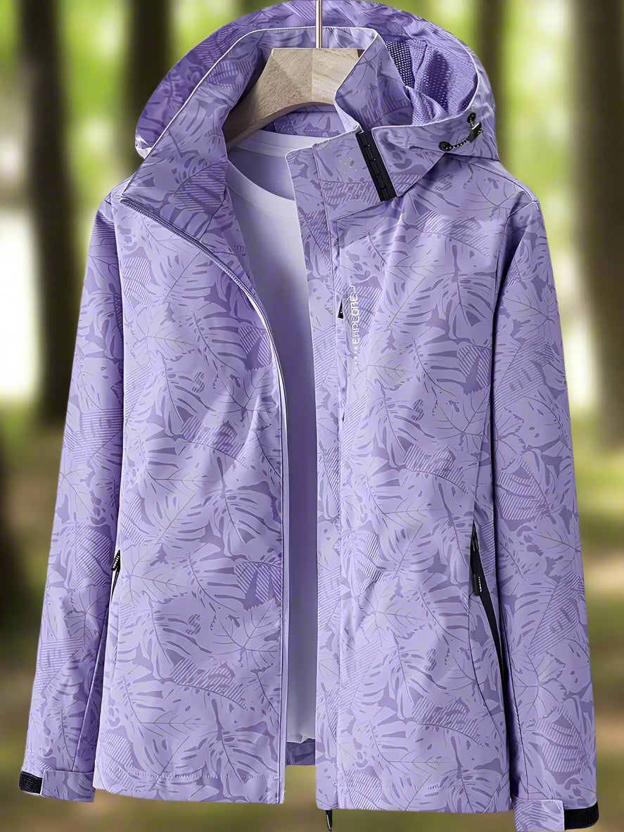 Flat lay of a black waterproof women's rain jacket with leaf print detailing on a white background