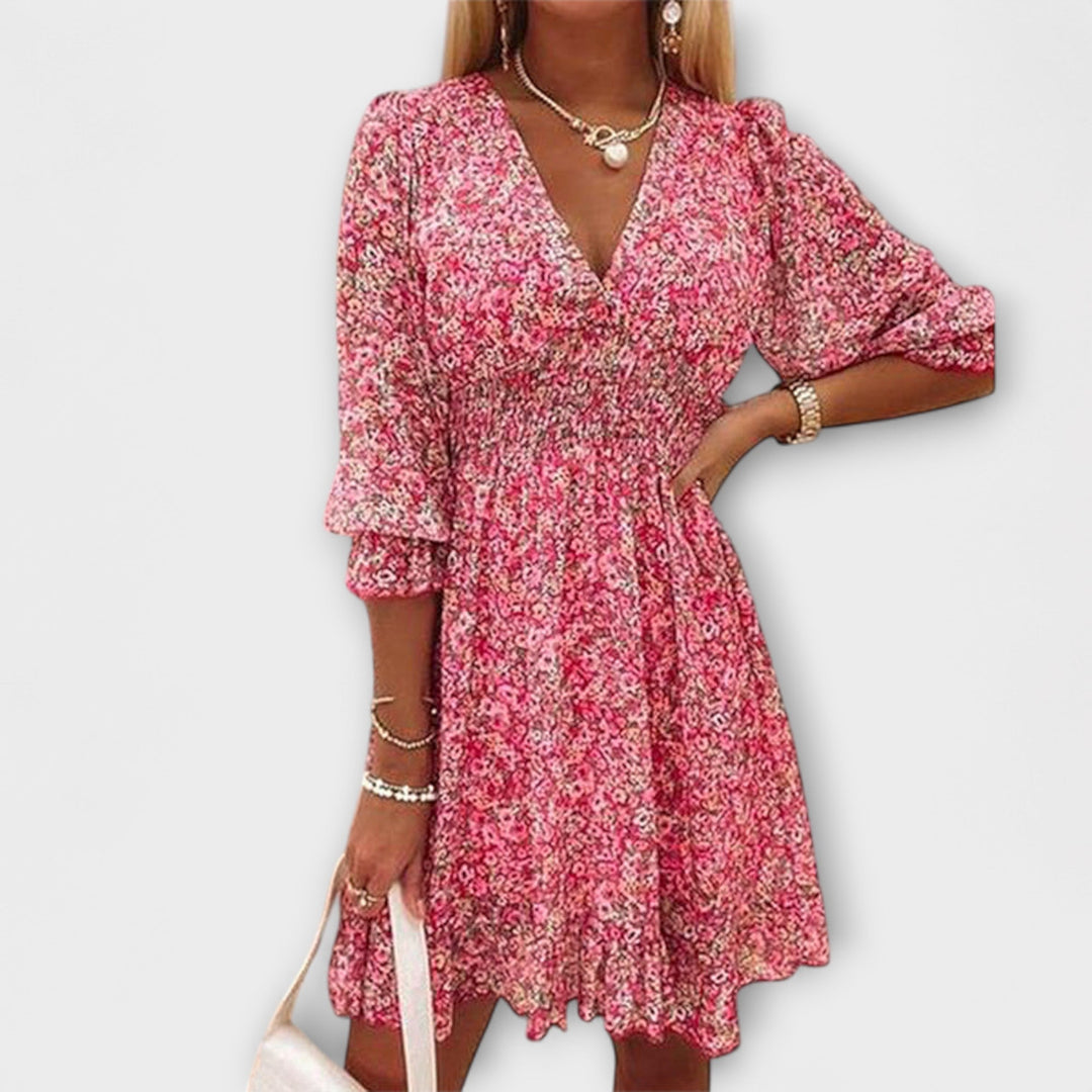 Woman wearing a pink floral puff sleeve dress with a gathered waist and flowing hem outdoors