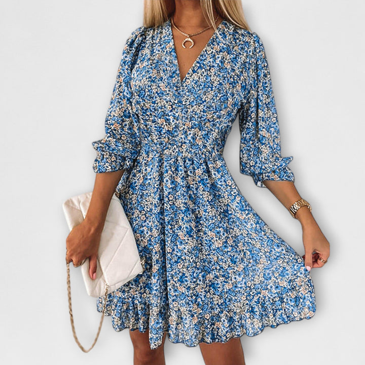 Woman in a green floral puff sleeve dress standing in a sunny outdoor setting