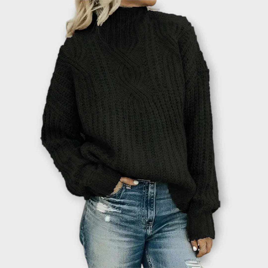 Woman wearing a relaxed-fit cable-knit mock-neck sweater in a neutral color, styled casually