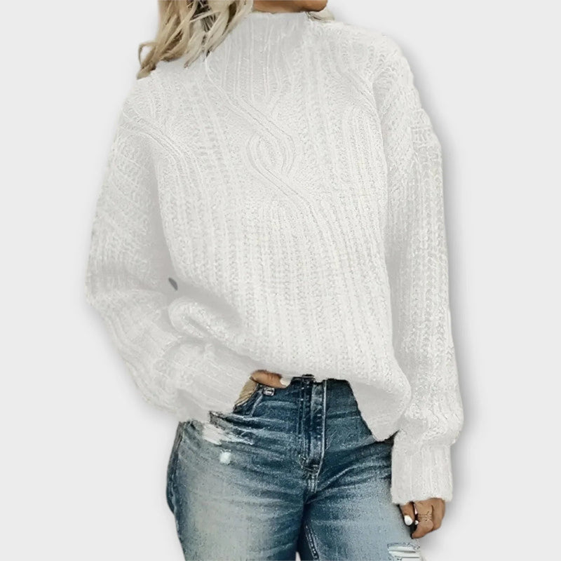 Side profile of a woman in a cable-knit mock-neck sweater paired with denim