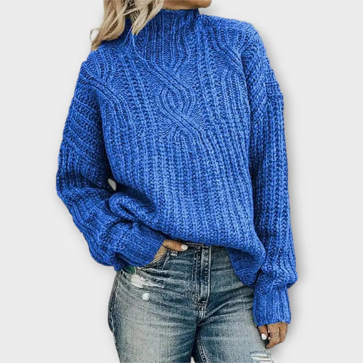 Flat lay of a modern high-neck cable-knit sweater showing color and texture detail