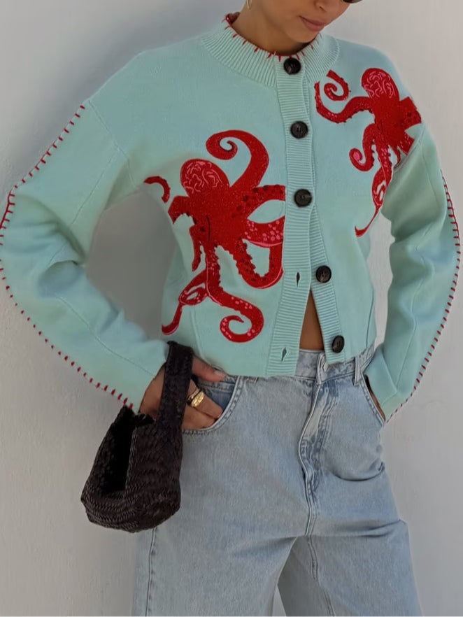 Close-up of the red octopus motif on a mint green cardigan knit fabric