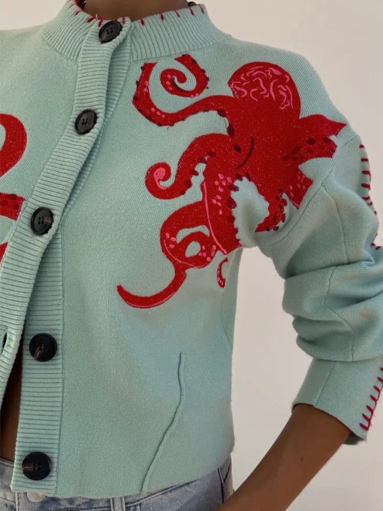 Detail shot of the cardigan hem and sleeve cuff in mint green with red octopus detailing