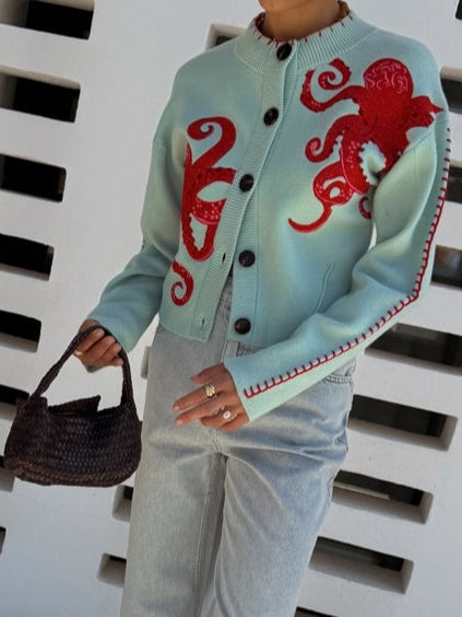 Full-length model shot of the mint green octopus cardigan paired with wide-leg trousers