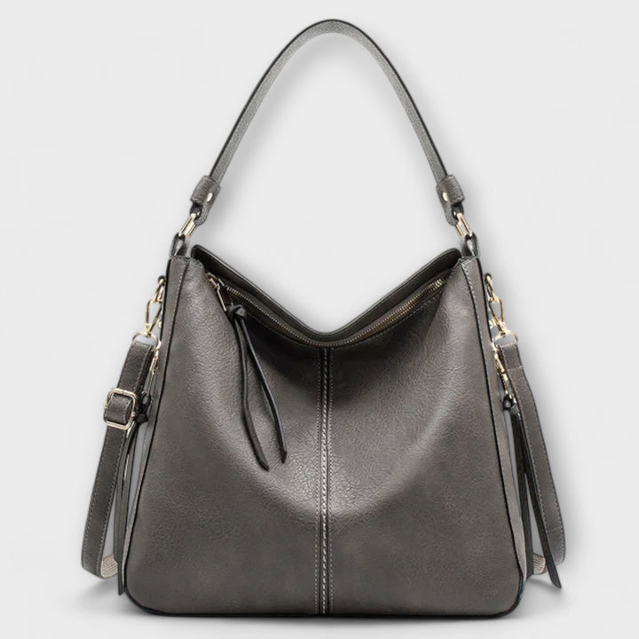 Lora shoulder bag in red held by model showing scale and proportion