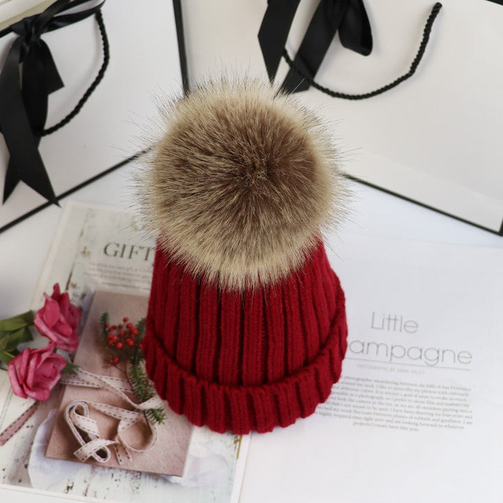 Woman smiling and wearing the Lorette pom beanie in navy blue