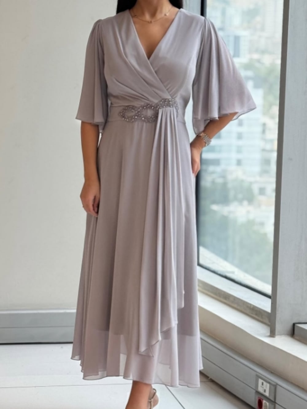 Model wearing a grey V-neck maxi dress with subtle textured panel detailing, front view