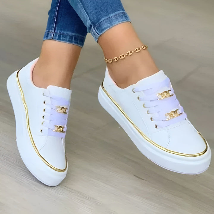 Pair of Luna white platform sneakers with gold chain detail, flat lay overhead view