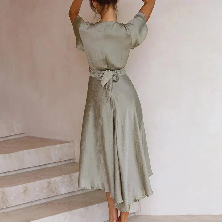 Side view of the Luna sage green satin midi dress showing the fluid drape and high-low ruffle hem