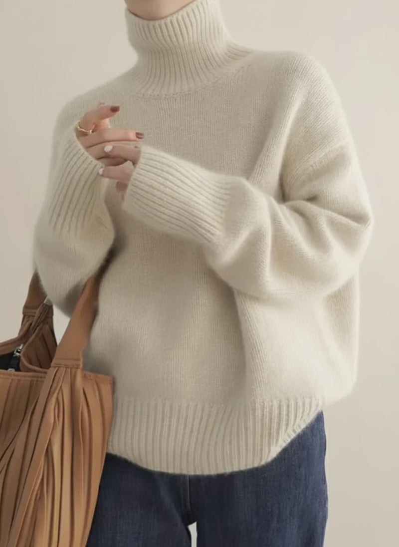 Model wearing a soft off white turtleneck sweater with a relaxed, elegant fit