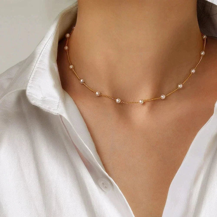 Close-up of a gold pearl necklace with a lustrous finish on a neutral background